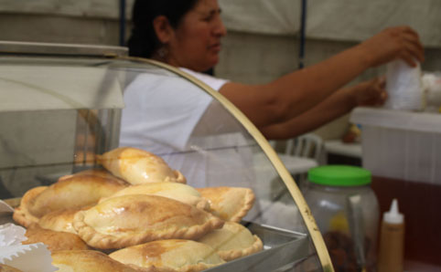 Mulher serve empanada na Praça Kantuta