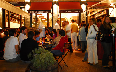 Patrons enjoy pizza in front of Bráz